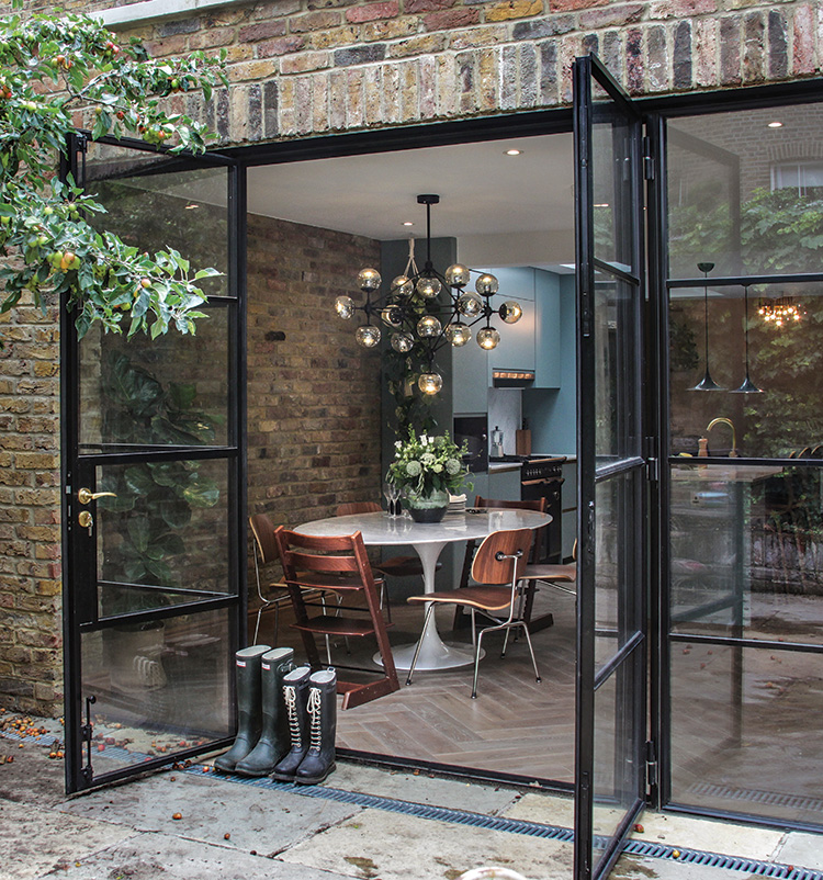 The black Crittall-style steel doors were a splurge, but essential in creating the seamless indoor-outdoor flow—the heart of the designer’s vision for the ground floor. The apple tree partially shading the courtyard produces a crop of small fruit every fall.