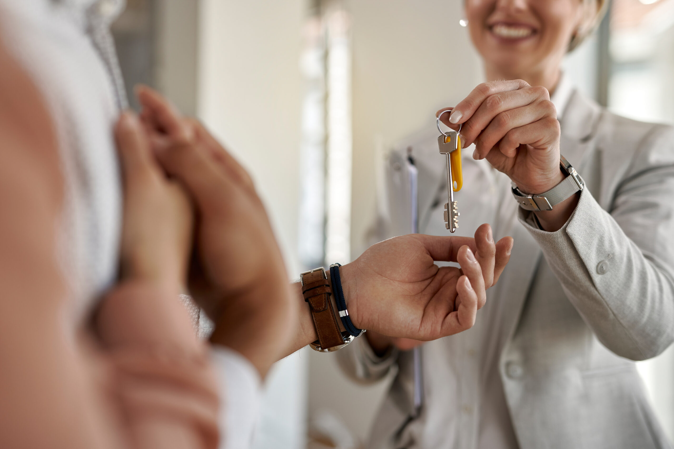 Close-up of a couple receiving keys of their new apartment from real estate agent.